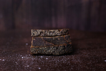 Pieces of black bread with sprinkled salt on a dark wooden background