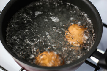 Two brown eggs in a pot of boiling water