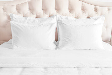 White pillows, duvet and duvet case on bed with beige headboard. - obrazy, fototapety, plakaty