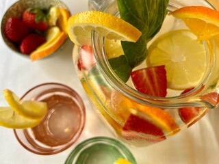 strawberry and lemon infused water in pitcher,  glasses and a fruit bowl  view from above