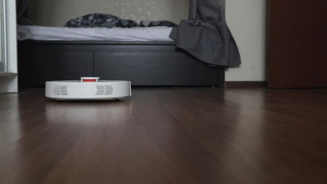 robot vacuum cleaner in a modern interior cleans the room, dusts in the bedroom, automated cleaning