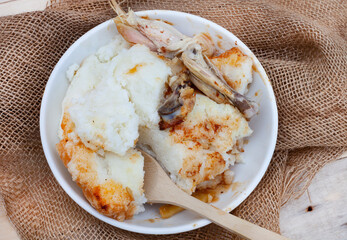 Popular and simple South African Fast food or street food, roasted chicken and pap or maize meal on a rustic surface