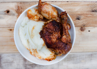 Popular and simple South African Fast food or street food, roasted chicken and pap or maize meal on a rustic surface