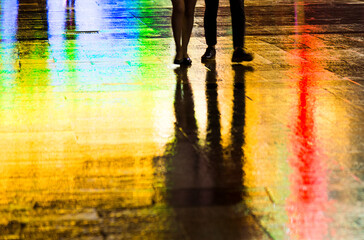 Silhouette of people walking at night on the wet street