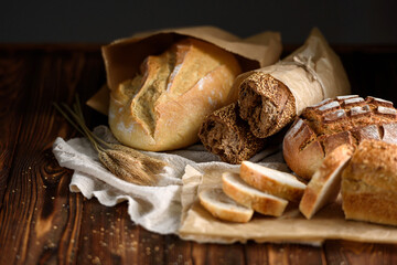 Bakery products on the kitchen rustic table. Various types of fresh fragrant crispy freshly baked bread on a wooden background. Appetizing bun and baguettes close-up. Healthy food and bakery concept.