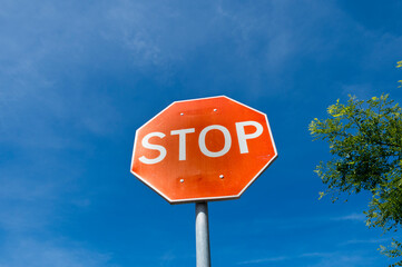 weathered red stop sign against a blue sky