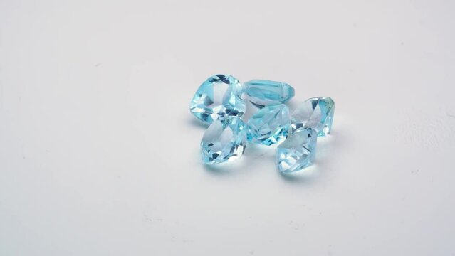 natural blue topaz gemstones on the white background turning table
