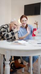 Obraz premium Grandfather and his adult granddaughter communicate with the family via video communication on the phone