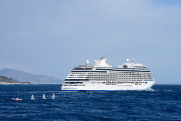 Obraz premium navire de croisière croisant la route de petits bateaux à voile en sortant du port - Méditerranée