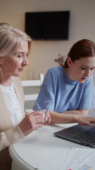 An elderly woman asks her daughter to help pay for purchases on the Internet using a credit card