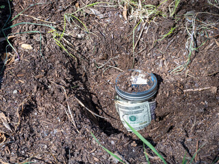 Burying a jar of money in the garden as savings, retirement or college fund concept.