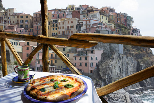 Italian pizza Margarita served on terrace overlooking to Riomaggiore, Cinque Terre