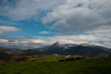 landscape with mountains, clouds and meadow.