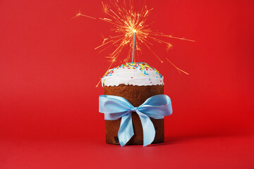 Easter cake with baw and sparkler on red background, easter food. minimal concept