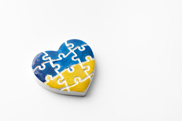 Heart in the form of puzzles with colors of the flag of Ukraine on a white background