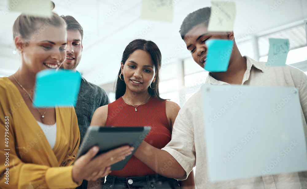 Poster Sourcing inspiration from the world online. Shot of a group of businesspeople using a digital tablet while brainstorming with notes on a glass wall in an office.