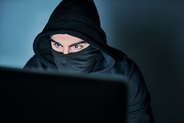 Hes on the hunt for your passwords. Shot of a young hacker using a computer late at night.