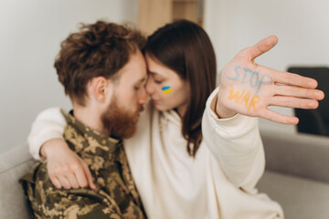 Ukrainian soldier in military uniform with his girlfriend showing a hand with the inscription stop war