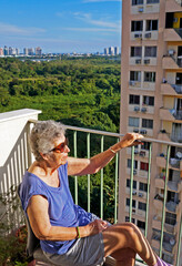 Fototapeta na wymiar Elderly woman sunbathing on the balcony, Rio de Janeiro
