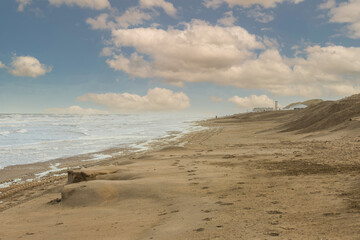 Coastal landscape of the Dutch North Sea coast near Noordwijk aan Zee during sunrise with the beach washed away by storms and the wind-smoothed calvings and foam flakes on the beach