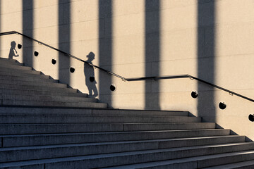 Stairs with the shadow of a woman, a child and columns. Street photography in Berlin, Germany