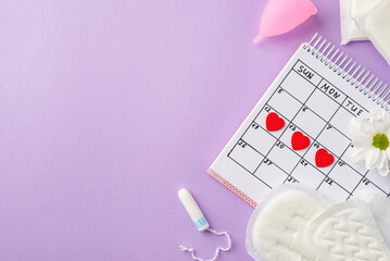 Top view photo of red heart marks on the calendar pink menstrual cup period pads tampon and camomile bud on isolated pastel violet background with copyspace - obrazy, fototapety, plakaty