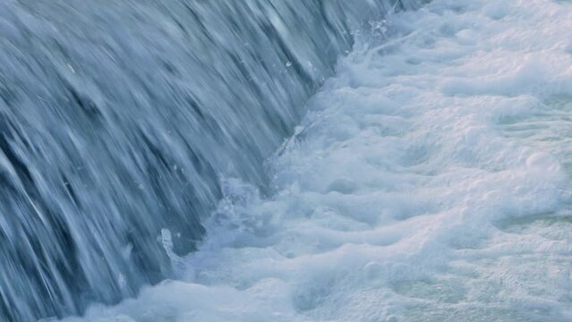 Flowing river water. Waterfall river cascade. Side view of a waterfall stream above a concrete dam. High quality FullHD footage