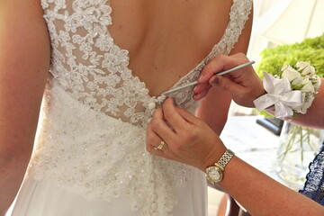 Obraz na płótnie Canvas Close up of Hands Doing Final Buttoning of Bride's Wedding Dress