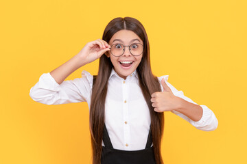 amazed child in school uniform and glasses for vision protection showing thumb up, knowledge