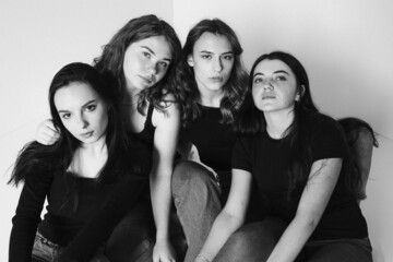 Group of female friends in a studio. three happy woman hugging together. Diverse group of women standing against a white background.