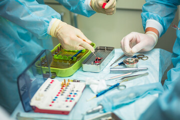 Professional dentist holding stomatological tool near the table with dental instruments in hospital during surgery