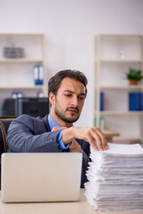 Fototapeta premium Young male employee and too much work in the office