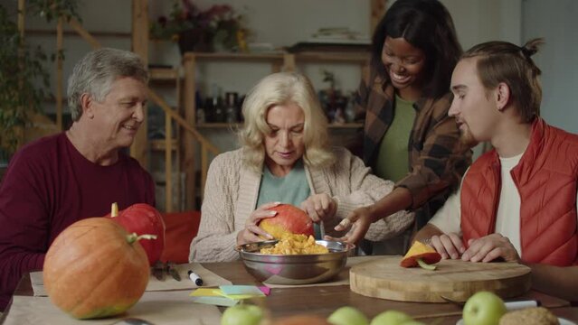 Family helping old lady to make a pumpkin for halloween