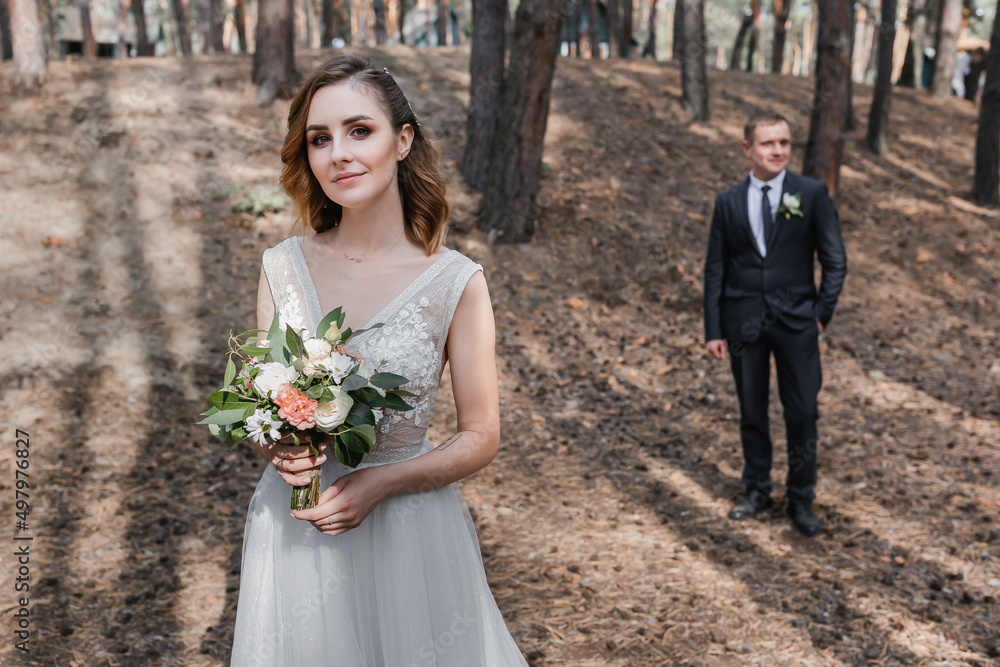 Wall mural Wedding couple in the park. An elegant bride of European appearance and a groom in a black suit.