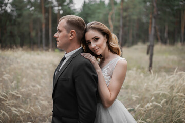 Wedding couple in the park. An elegant bride of European appearance and a groom in a black suit.