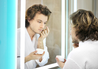 young man looking in the mirror,combing his hair,looking at problems on face.