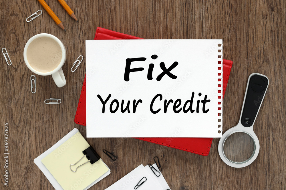 Poster fix your credit. notepad on the background of a wooden table. text on white paper of a red notepad n