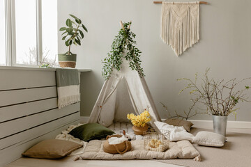 Spring children's photo zone with a wigwam. Children's interior. Rabbits, wigwam, spring branches, pillows, daffodils. Children's Easter photo zone with rabbits and chickens © Антон Романюк