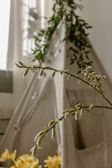 Flowering branch against the background of a children's wigwam. Spring photozone. Spring interior
