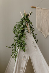 Ruscus greens on a children's wigwam. Spring composition