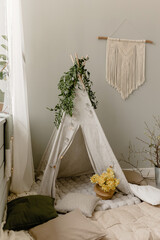 Spring children's photo zone with a wigwam. Children's interior. Rabbits, wigwam, spring branches, pillows, daffodils. 