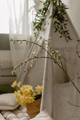 Flowering branch against the background of a children's wigwam. Spring photozone. Spring interior