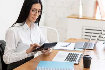 Asian woman working on her laptop in the office. Concept of businesswoman, female using technology, notebook, job in corporation, young professionals. Wearing glasses