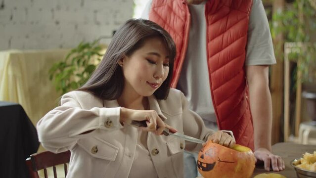 An adult girl starts carving eyes for a halloween pumpkin