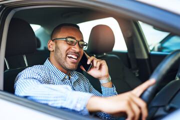 Im just around the block. Cropped shot of a young businessman talking on a cellphone while driving a car.