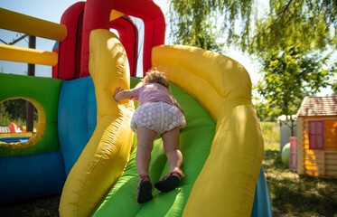 Fototapeta na wymiar the kid climbs on an inflatable slide in the summer