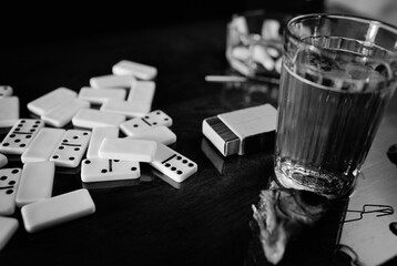 Leisure with a board game of dominoes. Scattered dominoes, a glass of beer, salted fish and matches...