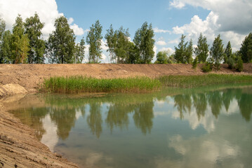 The beautiful lake reflects the trees on the shore in summer