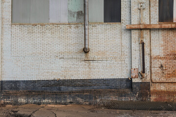 Pipe protruding from large brick wall on side of abandoned factory in small midwest town