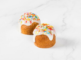 Easter cake with lemon sugar glaze, decorated with multicolored confectionery sprinkles. Light background